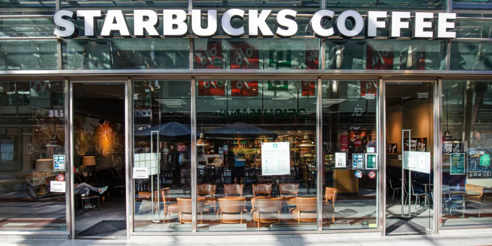 Мандрівник із чашкою кави біля кавʼярні Starbucks