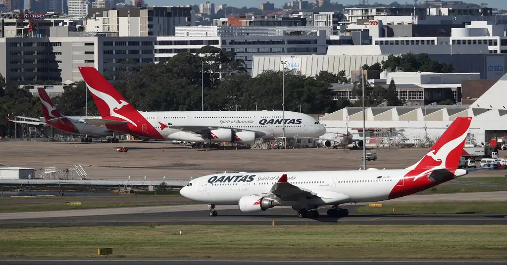 Наземні працівники Qantas біля літаків і вантажного обладнання в австралійському аеропорту